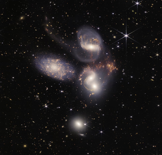 חמישיית סטיבן, על רקע הגלקסיות הראשונות ביקום, כפי שצולמה על ידי טלסקופ החלל ג'יימס ווב. שתי הגלקסיות הספירליות מצד שמאל בדרכן להתמזג. צילום: NASA, ESA, CSA, and STScI