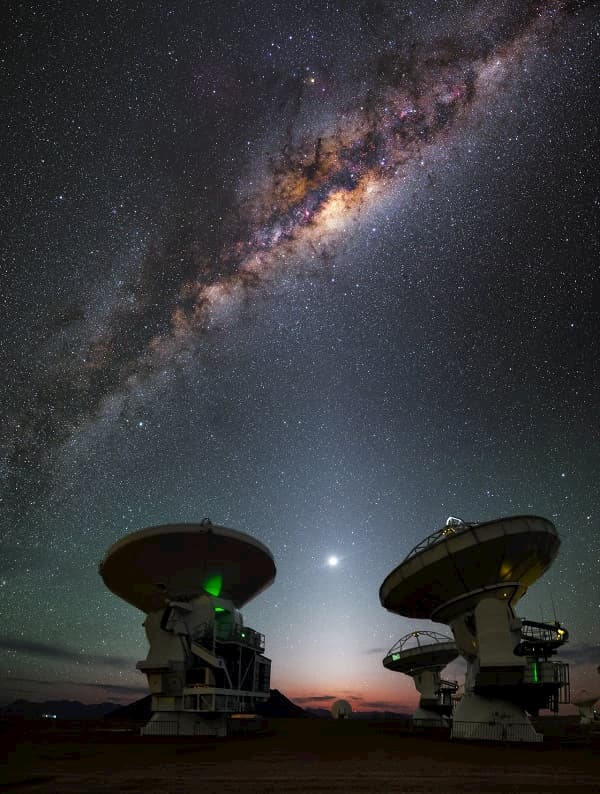  שמי הלילה מעל מצפה הכוכבים ALMA שבמדבר אטקמה, צ'ילה. שביל החלב חוצה את השמיים. במרכז, באזור הכי בוהק ואדמדם, נמצא החור השחור העל-מסיבי A* בקשת. קרדיט: ESO