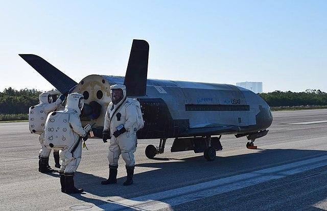 X-37B על המסלול, אחרי שחזר מהחלל. אנשי הצוות לובשים ציוד מגן מפני הקרינה. קרדיט: חיל האוויר האמריקאי